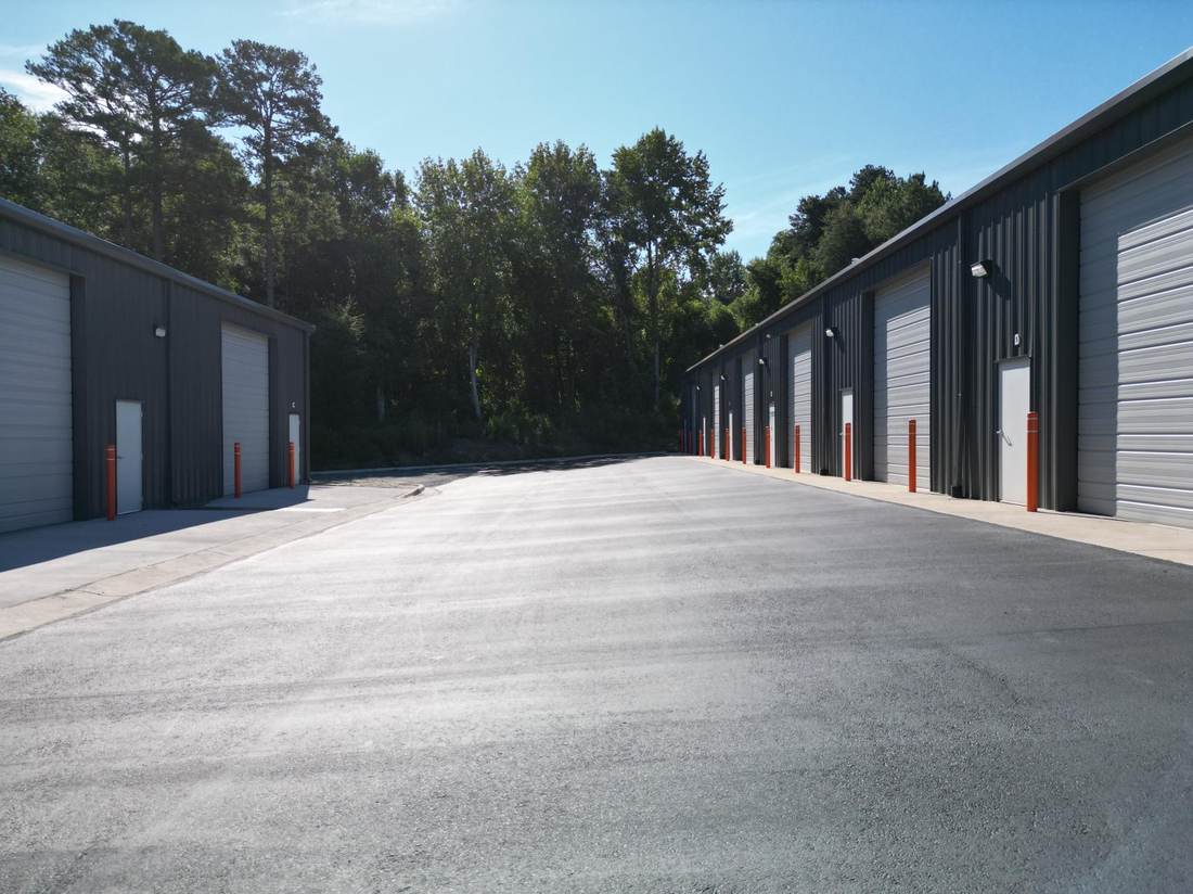 Drive aisle between two buildings with roll-up doors and orange bollards