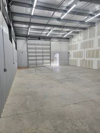 Unit interior looking toward a closed roll-up door and a personnel door
